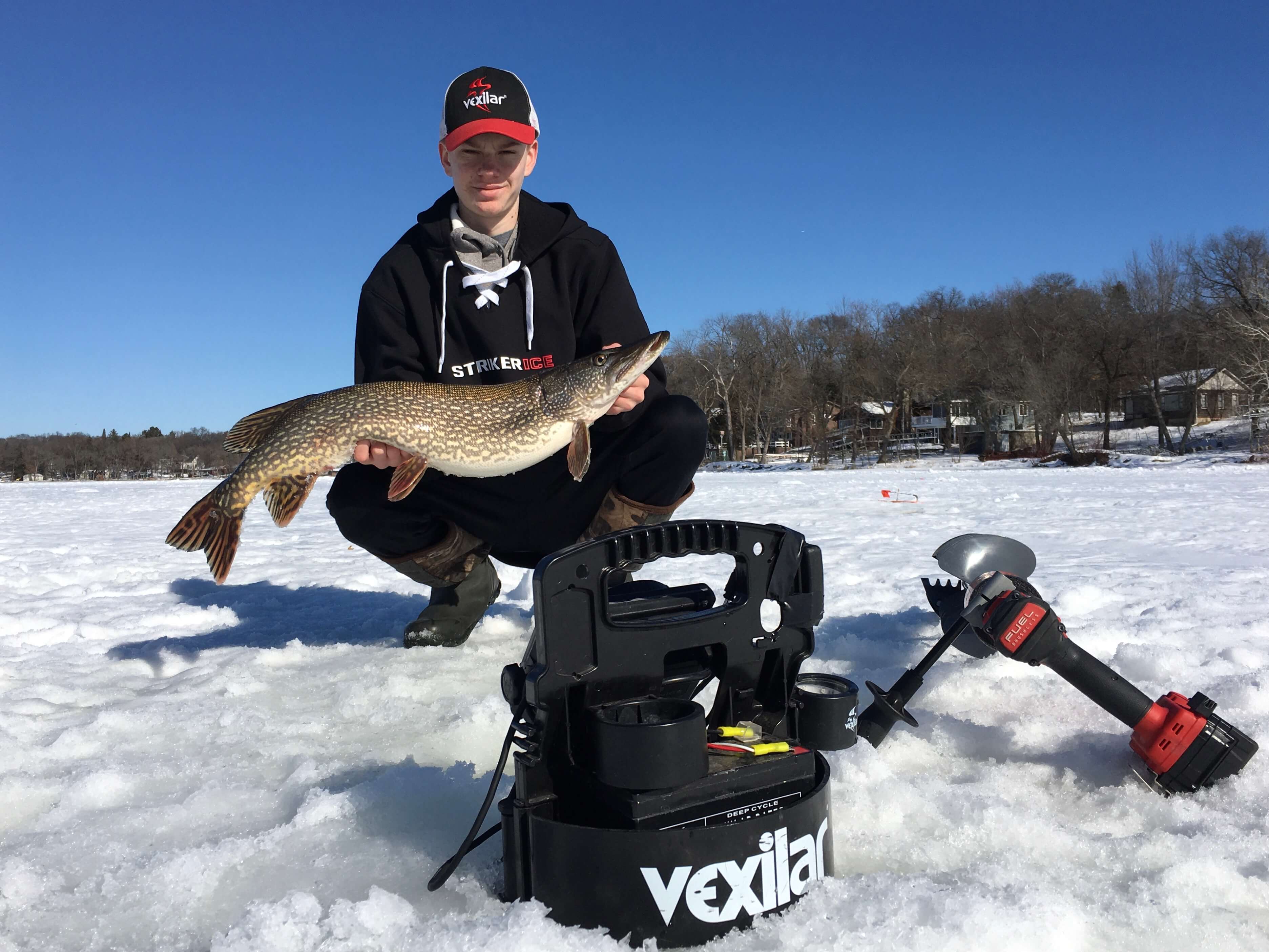 Angler kneeling with pike on ice