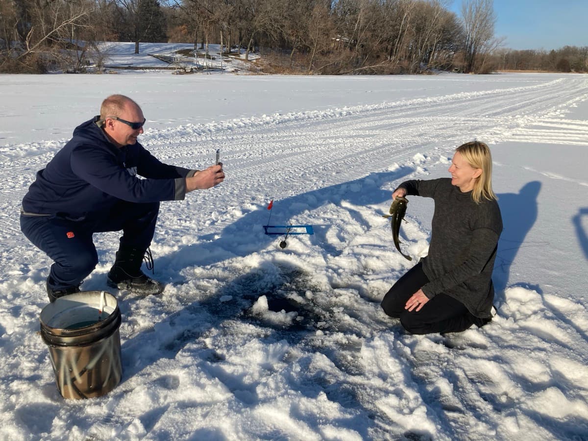 Action shot taking a picture of an ice fishing bass