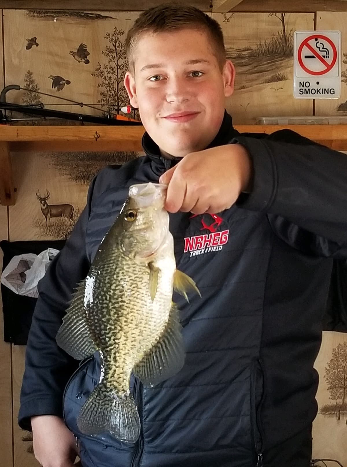 Kid with crappie inside the ice house