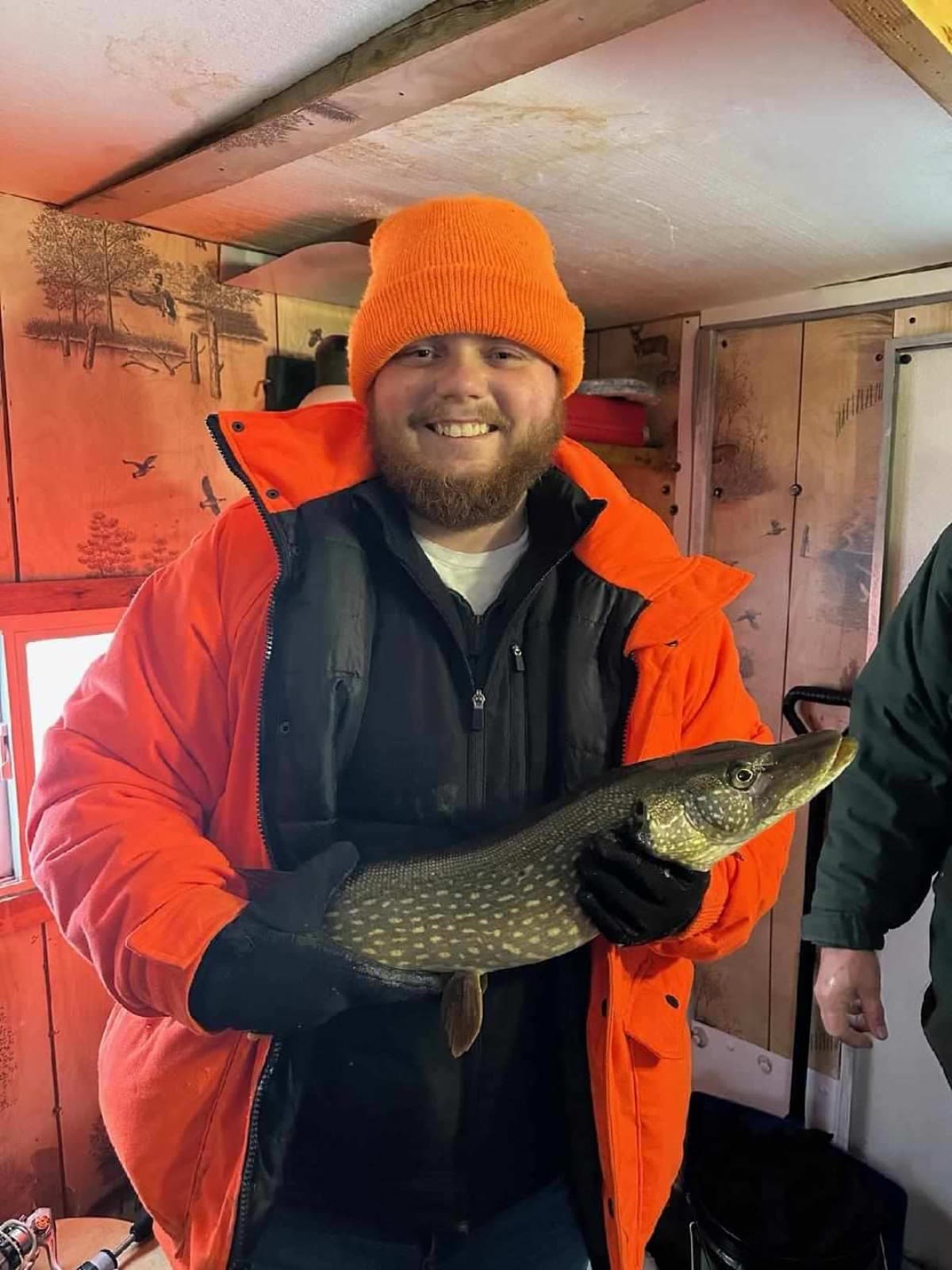 Happy angler with pike inside the ice house